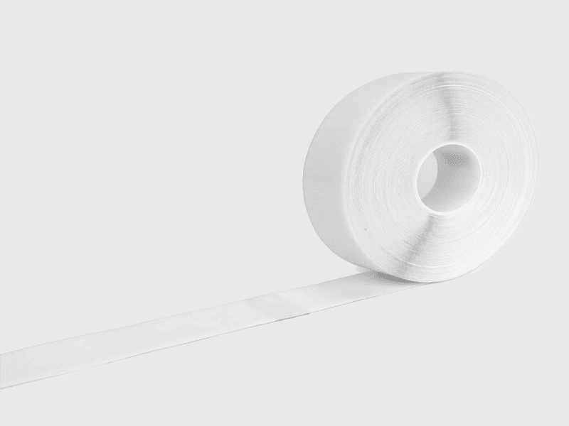 Een rol gespecialiseerde gymtapijt naast een emmer professionele lijm.